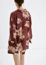 Camisa de manga larga color marrón con estampado floral grande en tonos beige y blanco, cuello camisero y cierre frontal con botones.