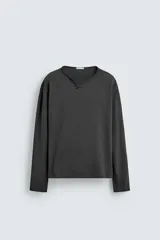 Camiseta de manga larga con corte relajado, confeccionada en algodón. Presenta un cuello redondo amplio con acabado irregular y detalle de botones frontales a tono.