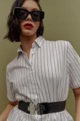 Camisa blanca con rayas verticales azul marino, de corte clásico, cuello camisero y manga corta.