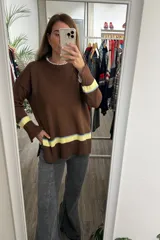 Sweater tejido de punto en color marrón, con cuello redondo y mangas largas. Presenta un diseño con franjas horizontales en tonos celeste y amarillo en los puños y en el ruedo inferior, con terminaciones acanaladas.