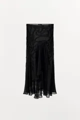 Falda midi negra de tiro medio con superposición de tejido transparente con diseño estampado y aplicación de abalorios a tono. Presenta bajo asimétrico con volantes y forro interior negro.