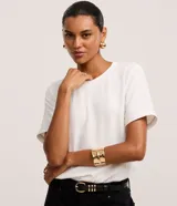 Blusa de manga corta color blanco con cuello redondo pespunteado, abertura tipo gota en la espalda con cierre de botón y efecto airflow.