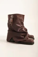 Botas marrones de cuero con caña arrugada, suela track y detalle de candado plateado.