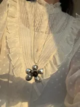 Collar largo plateado con dije de flor con centro negro.