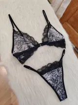 Conjunto de lencería compuesto por corpiño triangular y bombacha tipo tanga. El diseño combina microtul con estampado animal print y detalles de encaje negro en los bordes. El corpiño cuenta con cierre frontal y breteles regulables.