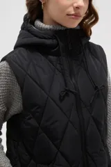 Chaleco largo acolchado color marrón, con diseño de rombos, cierre frontal completo y capucha ajustable con cordones.