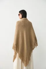 Ruana tejida en lana merino extrafina con lino y viscosa, de diseño triangular con textura en relieve y flecos en los bordes. Pieza versátil de calce holgado y envolvente.