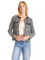 Chaqueta de tweed en tonos blanco y negro, con cuello redondo y abertura frontal. Presenta detalles de cinta con cadena en el cuello y en los bolsillos delanteros. Con forro interno.