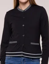 Cardigan tipo varsity negro de punto liviano, con cuello redondo, mangas largas y cierre frontal de botones. Presenta detalles de líneas blancas en el cuello, los bolsillos simulados y el ruedo elástico acanalado.