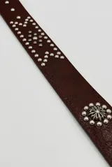 Cinto de cuero sintético marrón camel, con tachas metálicas plateadas decorativas y hebilla de metal envejecido.