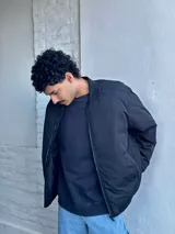 Campera bomber negra de nylon con cierre frontal y bolsillos laterales.