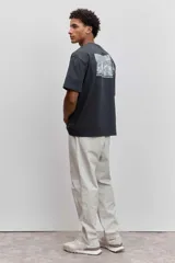 Remera de algodón color gris oscuro, de corte holgado y manga corta, con un pequeño estampado gráfico en el pecho.