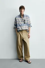Camisa de corte relajado confeccionada en tejido ligero de algodón, con diseño de cuadros en tonos azules y beige. Presenta cuello solapa, cierre frontal de botones, manga larga con puño abotonado y un bolsillo en el pecho.