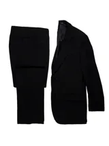 Traje de dos piezas color negro, compuesto por un saco con solapas clásicas y bolsillos frontales, y un pantalón de corte regular fit.
