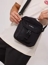 Bandolera negra de nylon con correa ajustable y logo Rusty estampado en blanco.