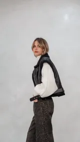 Chaleco de eco cuero negro con interior de corderito sintético, diseño oversize, cierre frontal y cinturón ajustable en el ruedo.