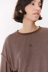 Remera de manga larga con corte oversized, color azul marino con cuello redondo en contraste color marrón. Presenta costuras decorativas a contratono hechas a mano en la zona de los hombros y logo bordado en el centro del pecho.