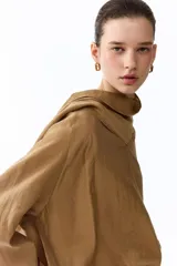 Blusa oversized de lyocell en color tostado, con cuello pañuelo drapeado y mangas largas raglán con puños anchos.