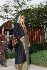 Tapado largo de sastrería con diseño bicolor y asimétrico. Una mitad presenta un tejido negro con rayas diplomáticas, mientras que la otra mitad es de un tejido a cuadros en tonos tierra. Cuenta con botones de nácar, bolsillos con tapa y abertura trasera.