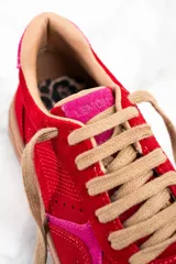 Zapatillas rojas de gamuza con detalles en rosa y suela marrón.