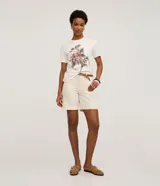 Remera blanca de algodón, corte slim fit, con cuello redondo y manga corta. Presenta un estampado bordado de flores rosadas y frutos con hojas verdes, acompañado de un pequeño texto en la parte inferior.