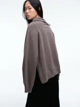 Sweater de lana superfina color gris, con corte holgado, mangas largas y cuello alto con medio cierre lateral.