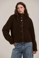 Campera de corderito color marrón, con cuello alto, cierre frontal con botones y terminaciones con ribete al tono.
