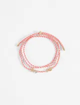 Pulsera de cordón rojo y blanco con dijes metálicos dorados en forma de corazón y tréboles.