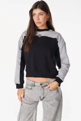 Buzo de cuello redondo con diseño de bloques de color en gris y negro, mangas largas y detalle bordado en el pecho.