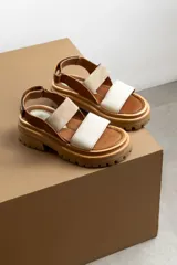 Sandalias de plataforma con suela track, combinando cuero marrón, gamuza beige y tiras frontales en cuero blanco. Cuentan con ajuste de hebilla en el tobillo.
