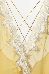 Vestido midi de georgette en color amarillo, con escote en pico y tirantes finos dobles cruzados en la espalda. Presenta detalles de encaje en contraste, bajo asimétrico con abertura frontal y volantes.