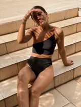 Top de bikini de un solo hombro con diseño bicolor, combinando negro y tostado. Está confeccionado en tejido de punto de alta calidad con propiedades de secado rápido y protección.
