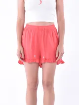 Short de tela fluida color coral, con cintura elástica, cordón de ajuste y detalle de volados en el ruedo.