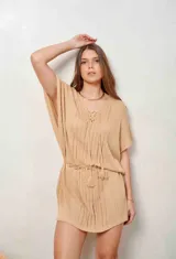 Poncho de hilo tejido en color blanco, con diseño translúcido, escote en V con cordones y borlas colgantes, y mangas murciélago amplias.