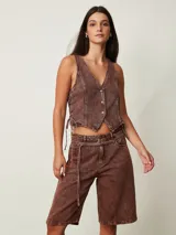 Top estilo chaleco crop de denim marrón con efecto acid wash, escote en V, cierre frontal con botones metálicos y cordones ajustables en los laterales.