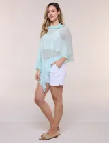 Poncho liviano de tejido de punto fino calado, color blanco, con silueta asimétrica envolvente, escote bote drapeado y mangas integradas estilo capa.