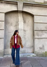 Campera tipo bomber color camel, confeccionada en gamuza, con bordados decorativos en tonos natural y bordó en las mangas y hombros. Presenta cierre frontal y diseño holgado.