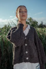 Cárdigan tejido de boucle color gris oscuro, con escote en V, mangas largas abullonadas y cierre frontal con botones grandes. Corte holgado.