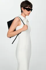 Vestido midi de tejido fluido y diseño entallado, con cuello de solapa y cierre frontal de cremallera. Presenta un corte sin mangas y un estilo minimalista.