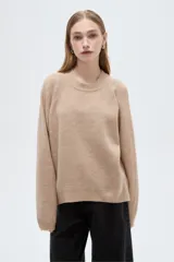 Sweater holgado de punto color beige con cuello redondo a la base y mangas largas raglán.