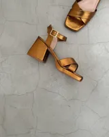 Sandalias de cuero color bronce, con taco cuadrado y tiras cruzadas en el empeine.