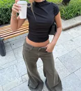 Jean de corte flare y tiro bajo, color verde oliva con costuras frontales verticales y ruedo desflecado.