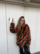 Buzo de peluche con estampado animal print tipo tigre en tonos marrón y negro, de corte holgado y manga larga.