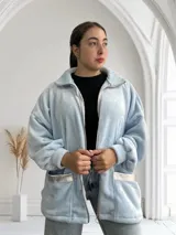 Campera celeste de tela tipo peluche, con cierre frontal, cuello alto y bolsillos con ribete plateado.