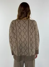 Sweater de lana color bordó con cuello alto y diseño de rombos y líneas verticales en rojo. Tiene puños y dobladillo acanalados.