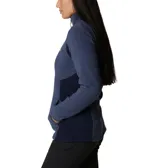 Campera polar de mujer con cierre completo frontal, cuello alto y bolsillos laterales. Presenta un diseño entallado con paneles laterales en un tono de azul más oscuro y el logo de la marca bordado en el pecho.
