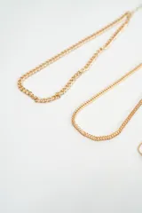 Set de tres brazaletes dorados de diferentes estilos: uno de cadena gruesa, uno de cadena fina tipo serpiente y uno de cadena fina con dije de trébol y cuentas esféricas.