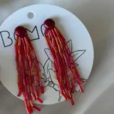 Par de caravanas colgantes con cuentas tubulares rojas, fucsias y doradas, con base redonda color borgoña.