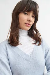 Sweater de tejido de punto color beige, con escote en V profundo, mangas largas y fit holgado.