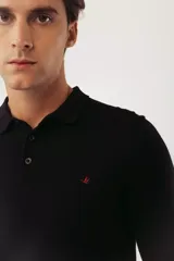 Sweater de punto estilo polo, color negro, con cuello camisero, cierre frontal de botones y mangas largas con puños acanalados. Presenta un pequeño logo bordado en el pecho.